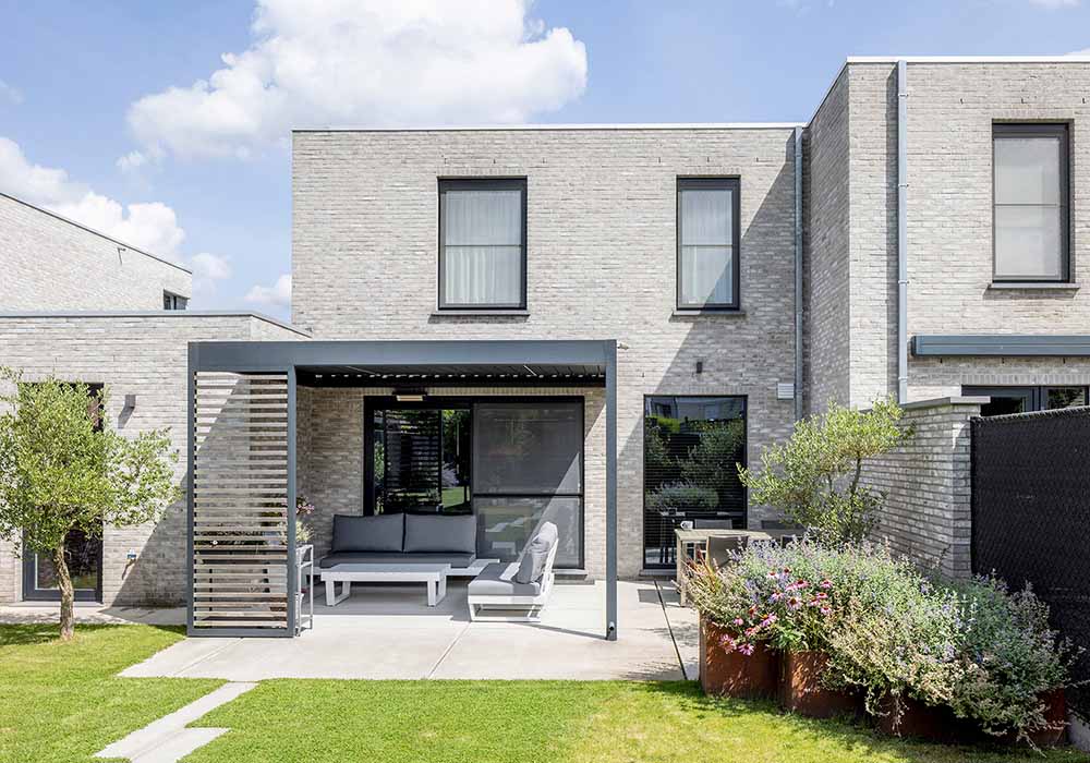 Compacte moderne woning met houten terrasoverkapping en grote schuifraampartij naar de tuin.