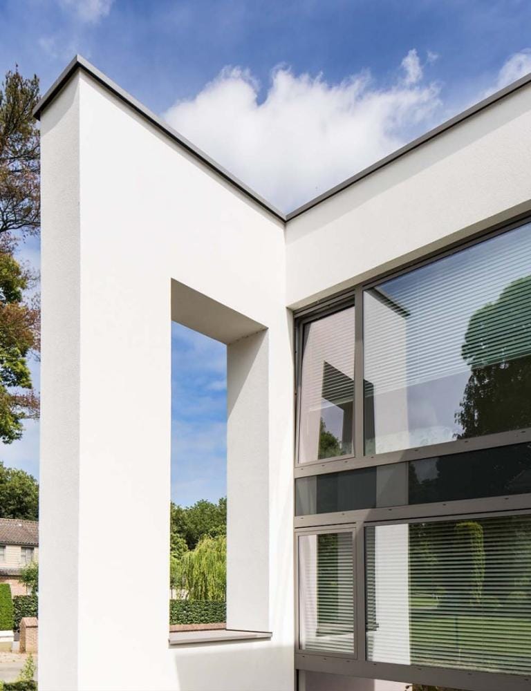 Realisatie in lichte crepi met grote raampartijen die een open relatie met de tuin creëren.