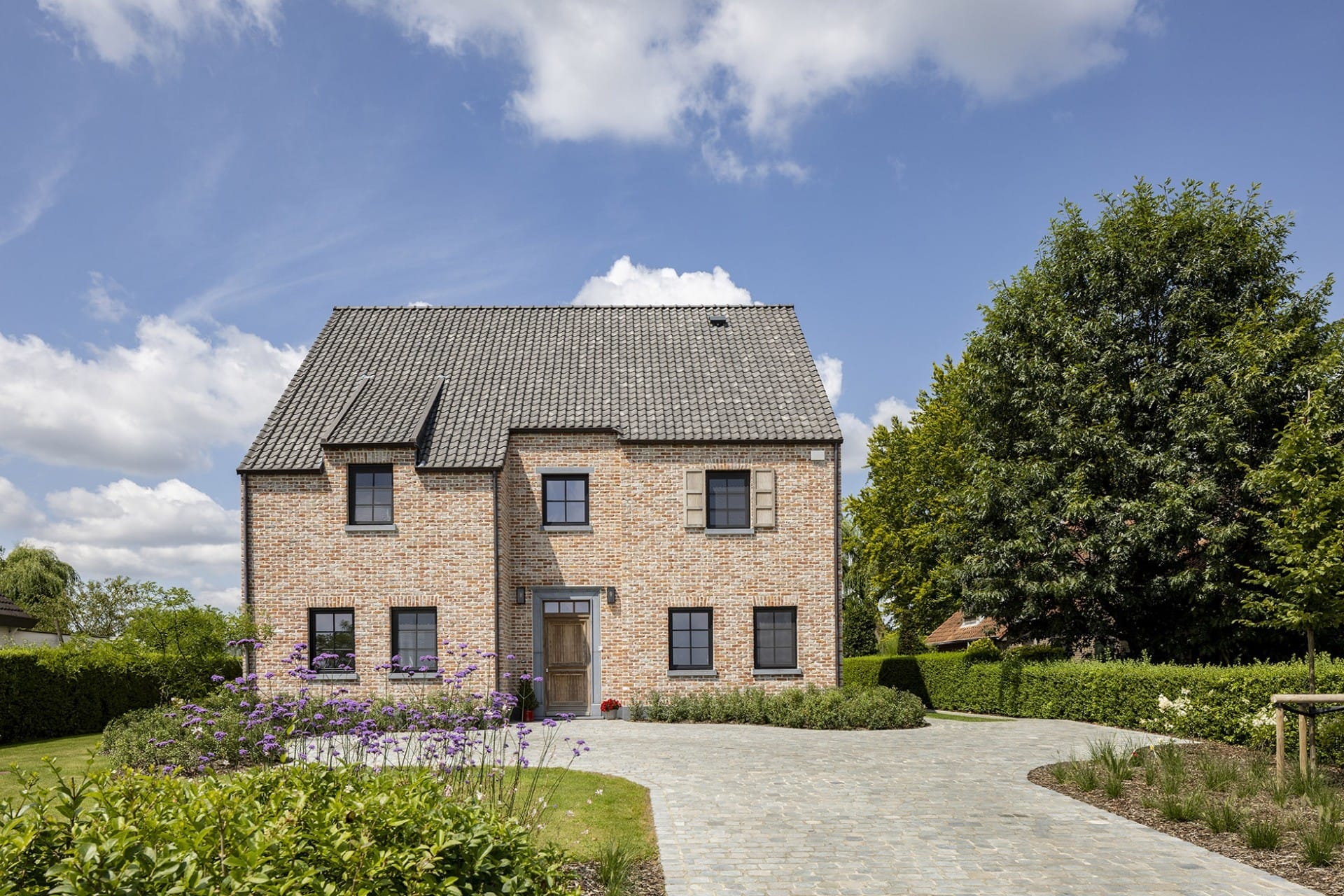 Rustieke nieuwbouwwoning in landelijke stijl met klassieke gevelsteen en donkere pannen.